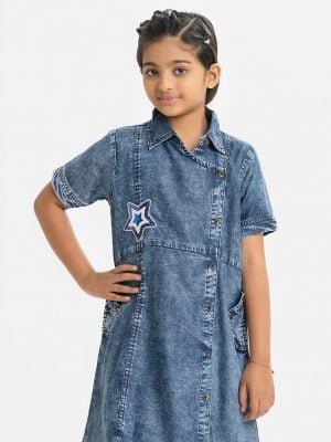 Kids girl A-line retro wrap style tunic in denim fabric. Classic collar, Short sleeved. Button fastening at the front. inseam pockets and attached patch at the front.