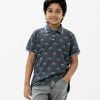 Kids boy Polo Shirt in cotton pique fabric. Classic collar, short sleeves and all over dinosaur printed.