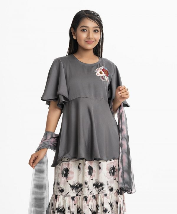 Teen girl's skrit top set in crepe and georgette fabric. Round neck, butterfly-sleeved peplum-style top. Embroidery and karchupi at the top front. Complemented with tiered skirt and tie-dye printed chiffon dupatta.