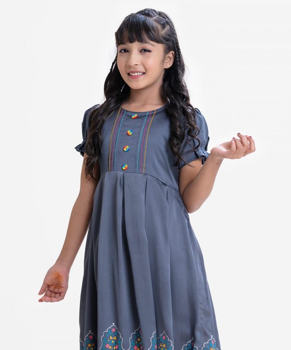 Kid girls frock in crepe fabric. Puff sleeved, colorful stitching and buttons at front. Box pleats at waist.