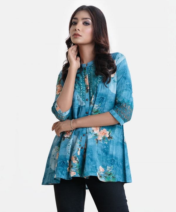 Ladies' shirt in printed georgette fabric. Stand collar, three-quarter sleeves. Metal buttons front opening with lace work at front.