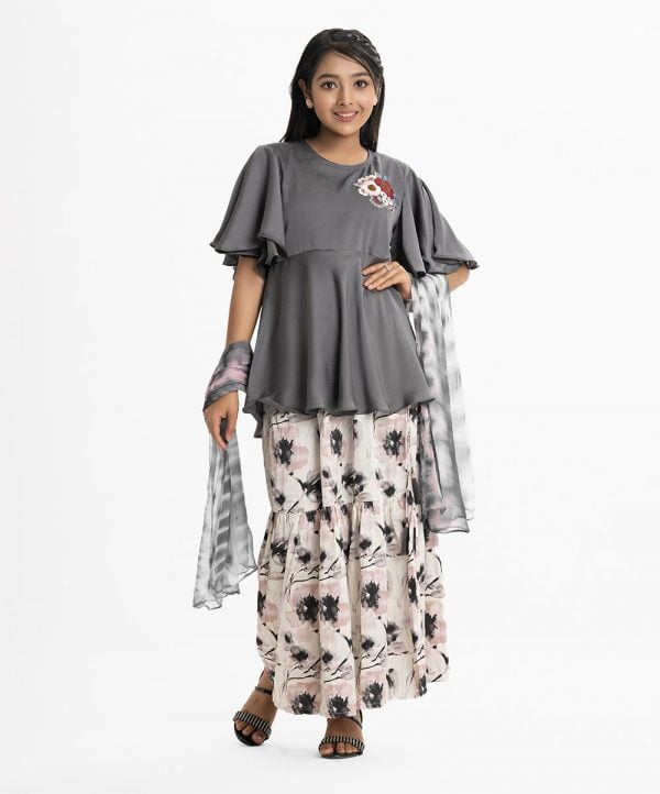 Teen girl's skrit top set in crepe and georgette fabric. Round neck, butterfly-sleeved peplum-style top. Embroidery and karchupi at the top front. Complemented with tiered skirt and tie-dye printed chiffon dupatta.