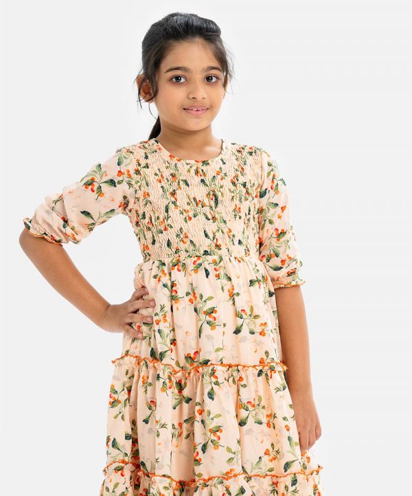 Kids girl layer style frock in printed georgette fabric. Round neck, puff-sleeved. Smokey and frill trim at the front.