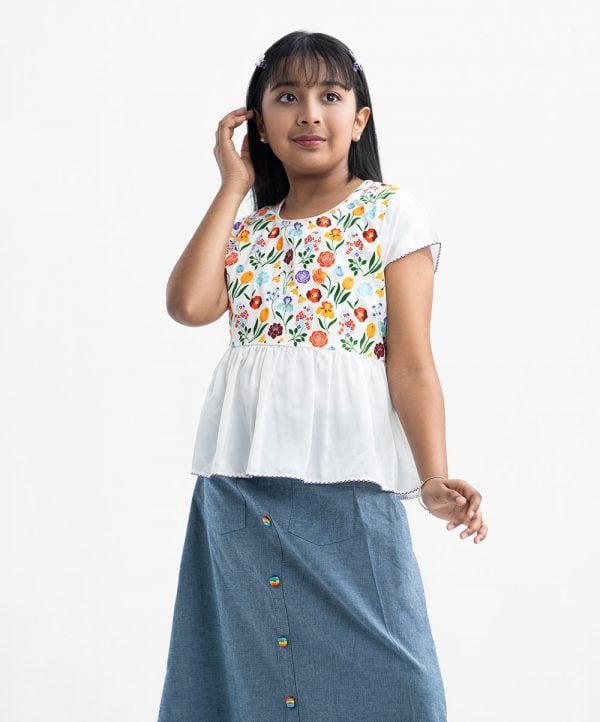 Kid girl's woven set in crepe and denim fabric. Round neck, Cap sleeves and a tassel tie-cord top. Two pockets with a show button at the front of the skirt.